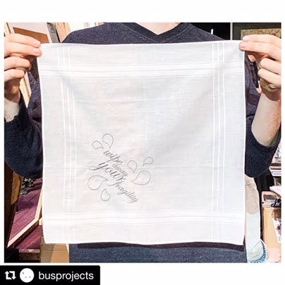 Person holding white hankerchief that shows embroidered text reading "wipe away your fragility"